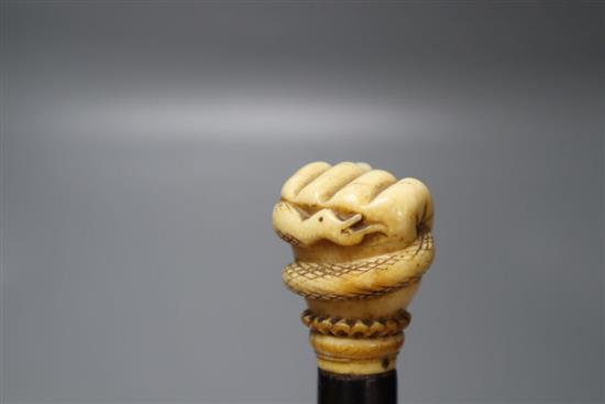 An ebonised walking cane, the handle of a carved ivory hand holding a coiled serpent, length 87cm